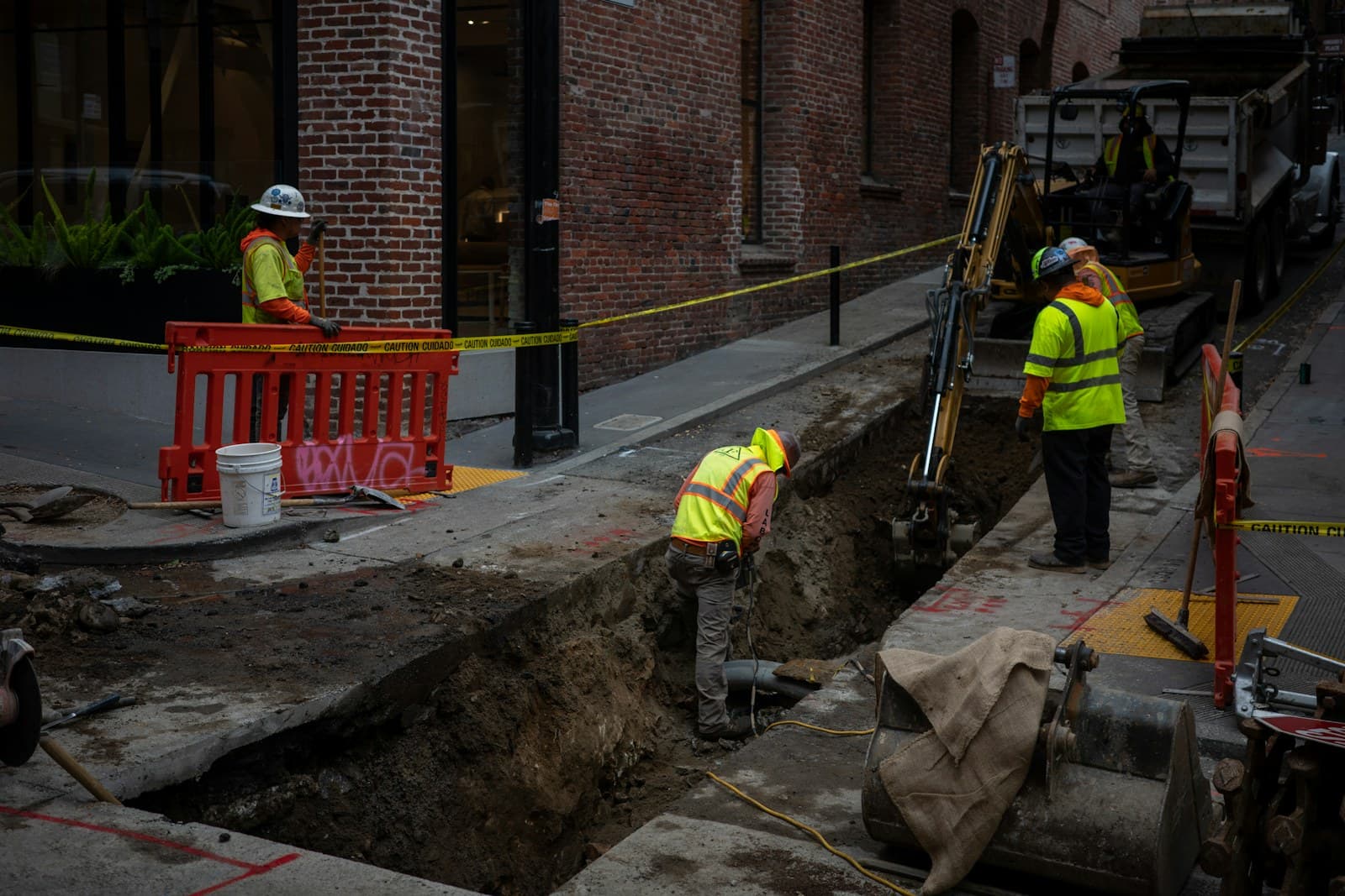 Construction workers excavating a trench along a paved city street for an underground utility line